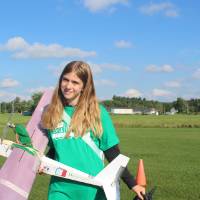Green team student poses with their plane adorned with world cup related doodles